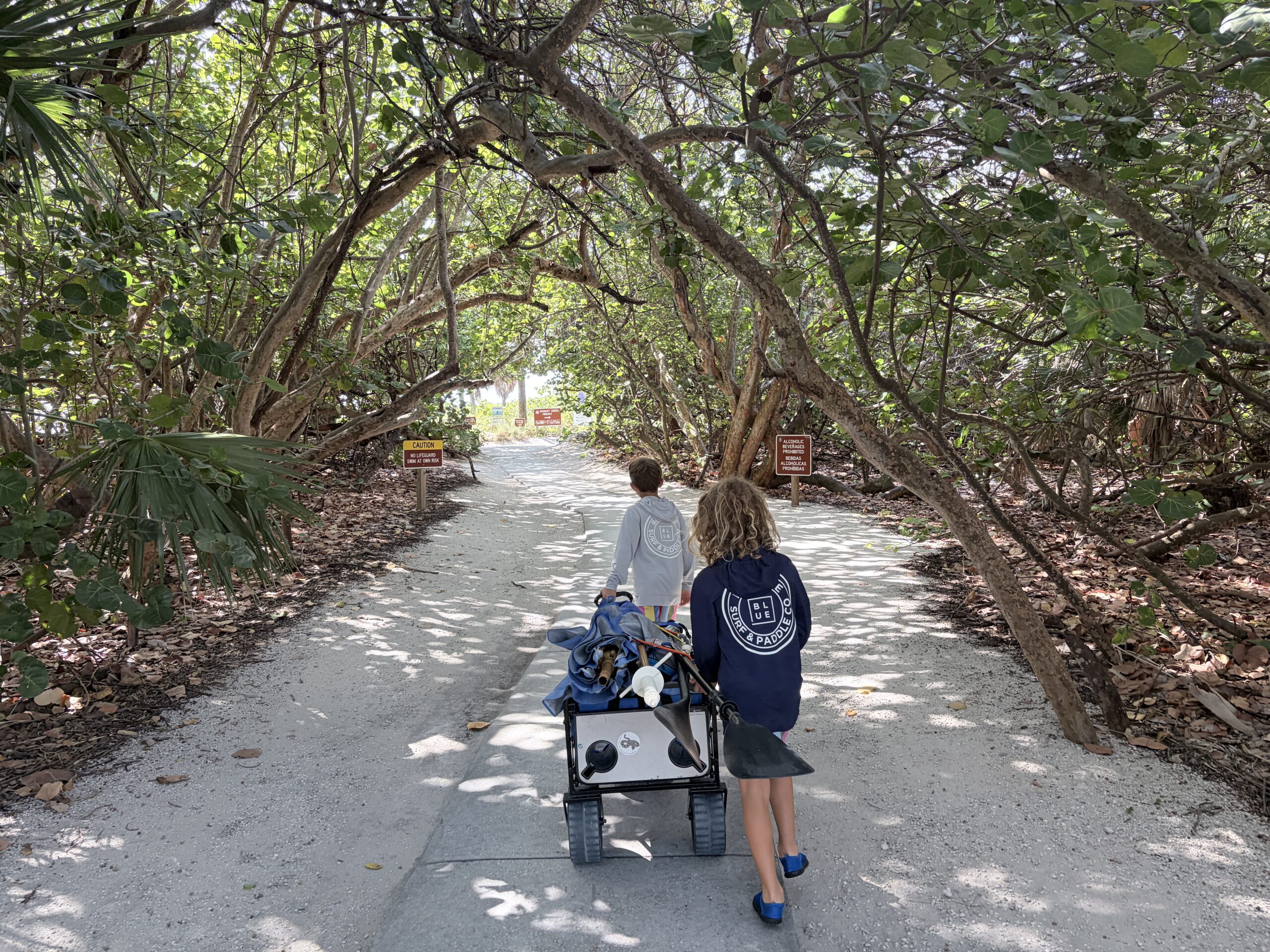 Two kids pulling a wagon through a mangrove tunnel at Mizell-Johnson State Park Dania Beach Florida