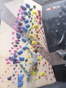 Boy climbing a colorful bouldering wall at Cultivate Climbing in Asheville, NC