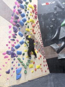Boy climbing a bouldering route with yellow holds at Cultivate Climbing