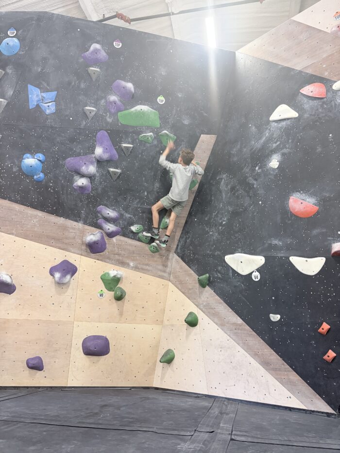 Boy climbing a colorful bouldering wall at Cultivate Climbing in Asheville, NC