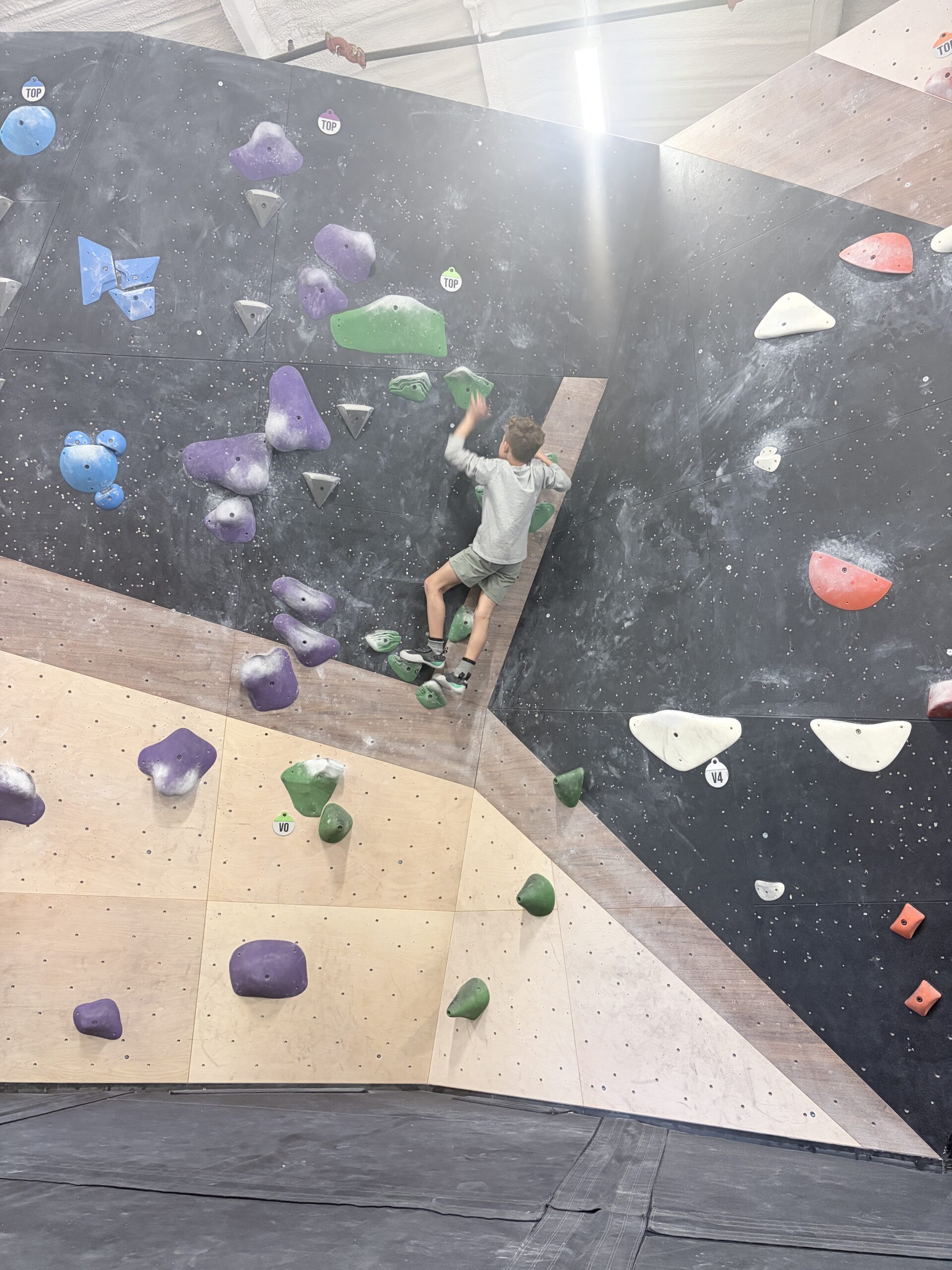 Boy climbing a colorful bouldering wall at Cultivate Climbing in Asheville, NC