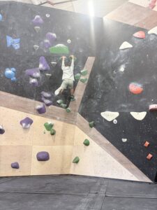 Kid reaching the top of a bouldering route on his first climbing gym visit