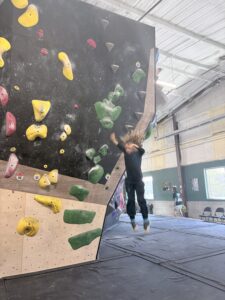 Kid bouldering on a white climbing wall at an Asheville climbing gym